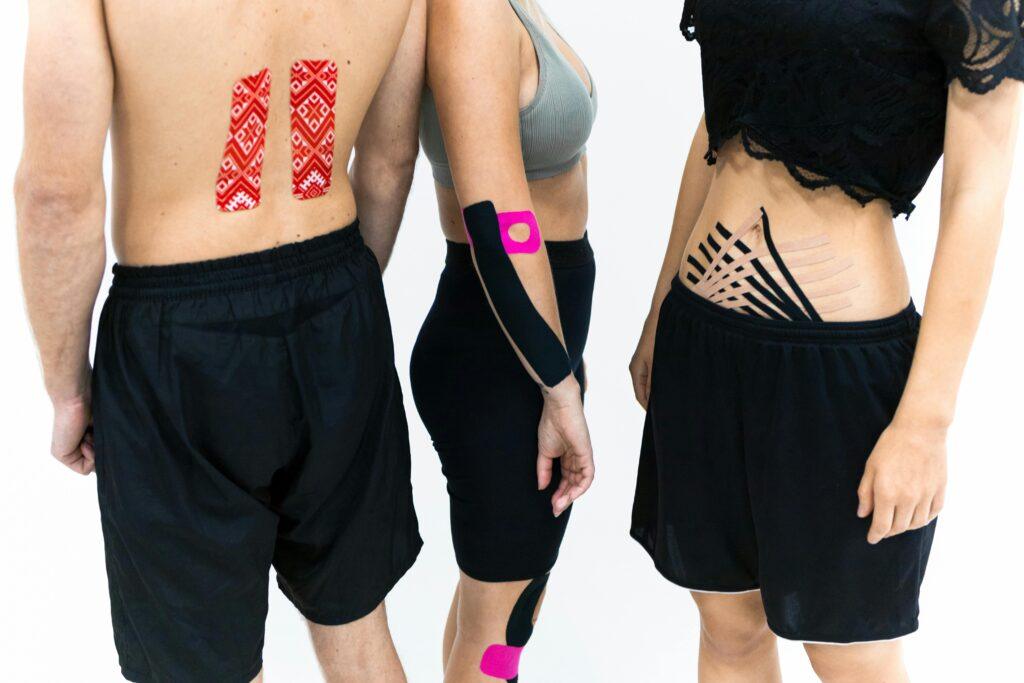 pexels-photo-6094335-6094335 Adults with kinesiology tape applied on back, abdomen, and arm for therapeutic support.