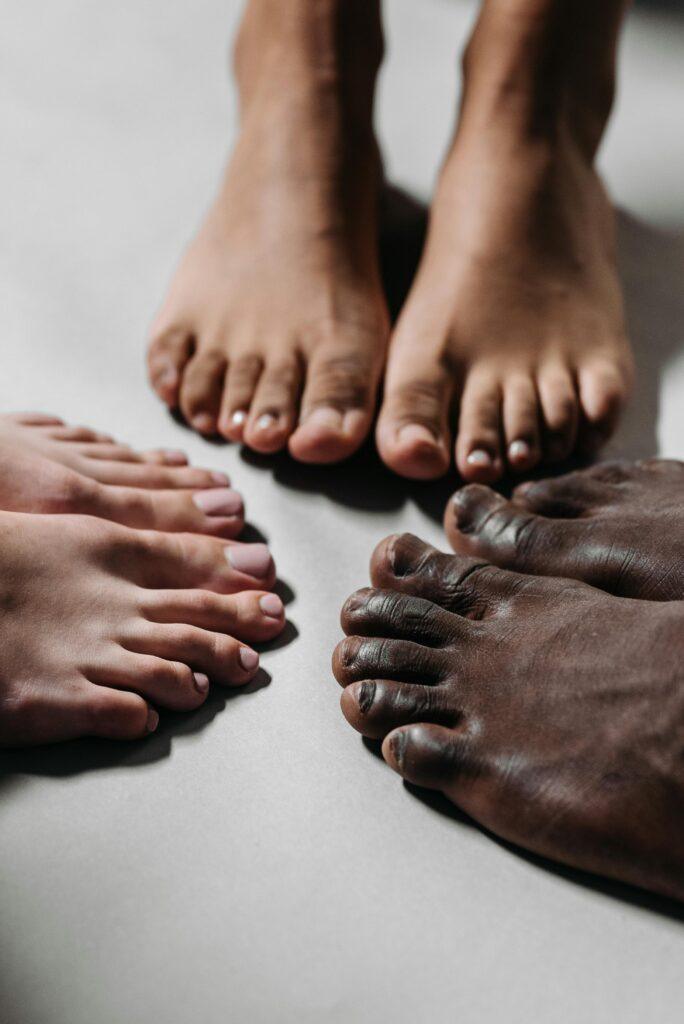 pexels-photo-9486780-9486780 Close-up of diverse feet together on a white surface, representing unity and diversity.