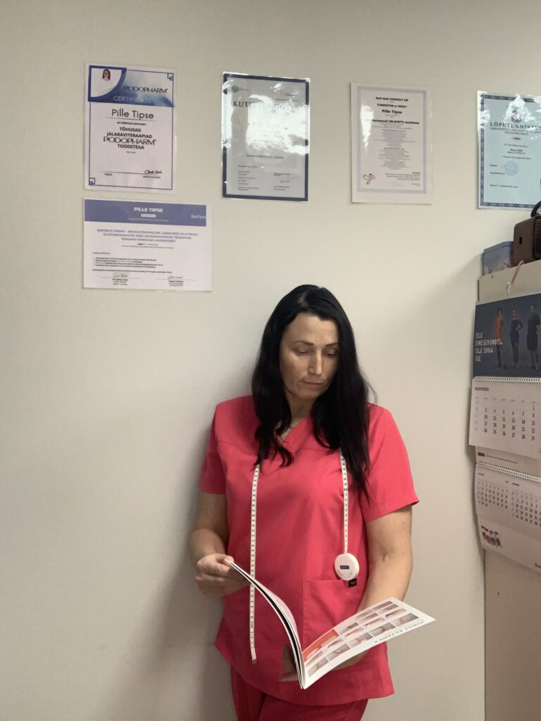 11 Abi omanik 11 Abi omanik mõõdulindi ja kompressioon toote kataloogiga seismas kalendri juures.Seinal näha erinevad diplomid